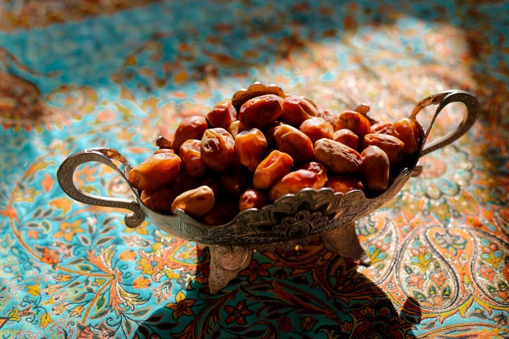A decorative silver bowl filled with dates, set on a vibrant Persian fabric, highlighting traditional Iranian culture.